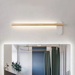 Slim wood vanity light lit above a mirror in a green bathroom
