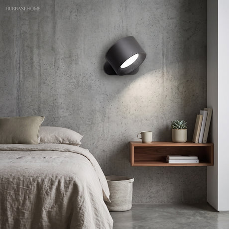 Black battery operated wall light mounted beside a bed as a reading light