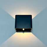 Black cube wall sconce lit on a blue wall showing both beams