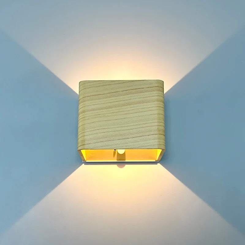 Wood finish cube wall sconce lit on a blue wall showing both beams