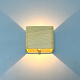 Wood finish cube wall sconce lit on a blue wall showing both beams