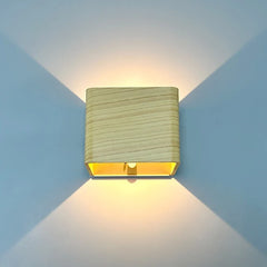 Wood finish cube wall sconce lit on a blue wall showing both beams