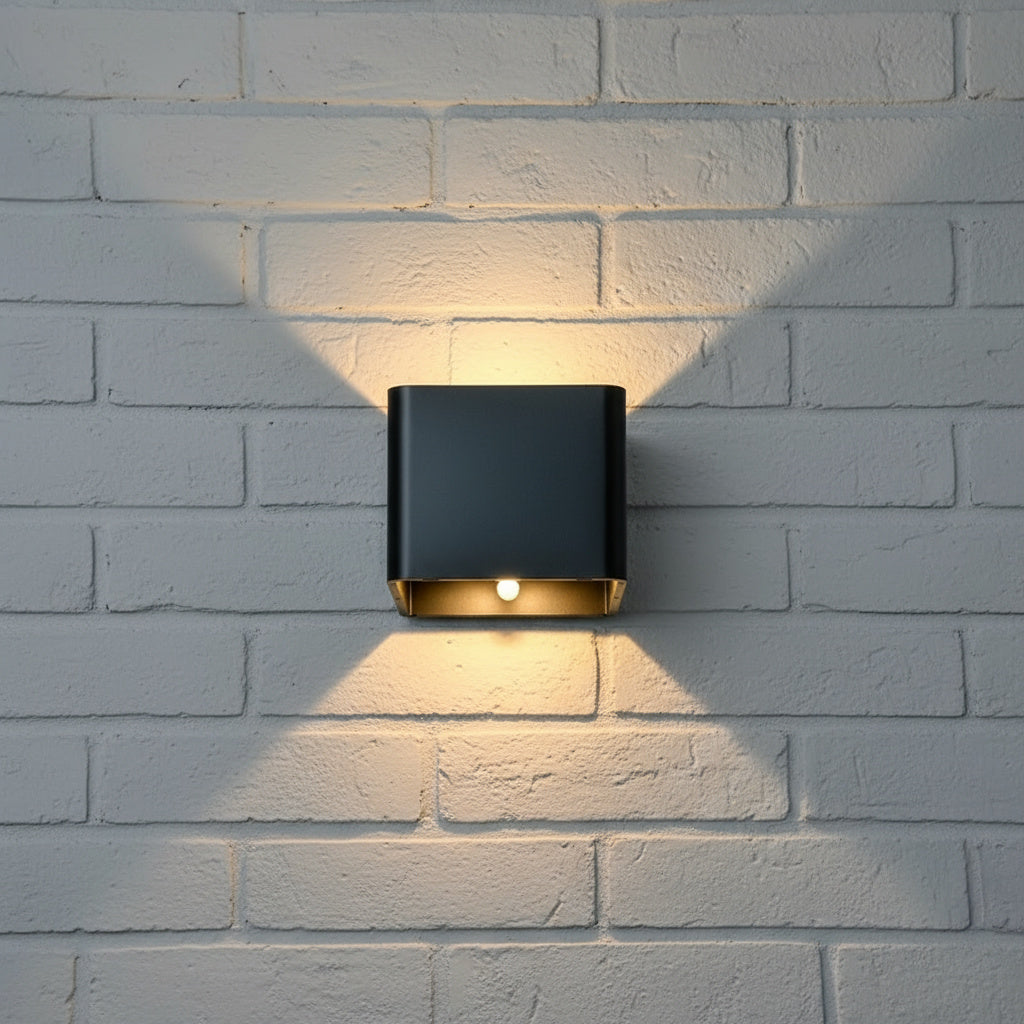 Black cube wall sconce lit on a white brick wall