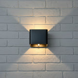 Black cube wall sconce lit on a white brick wall