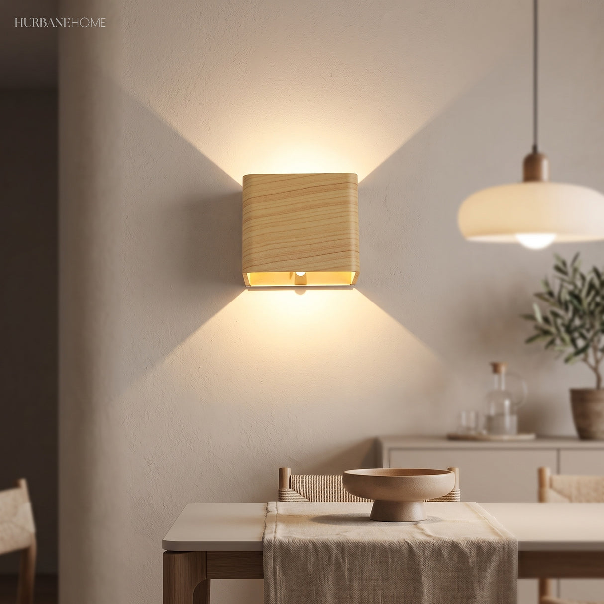 Wood finish cube wall sconce lit above a dining table