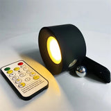 Black cordless light shown with its magnetic mount and remote handset
