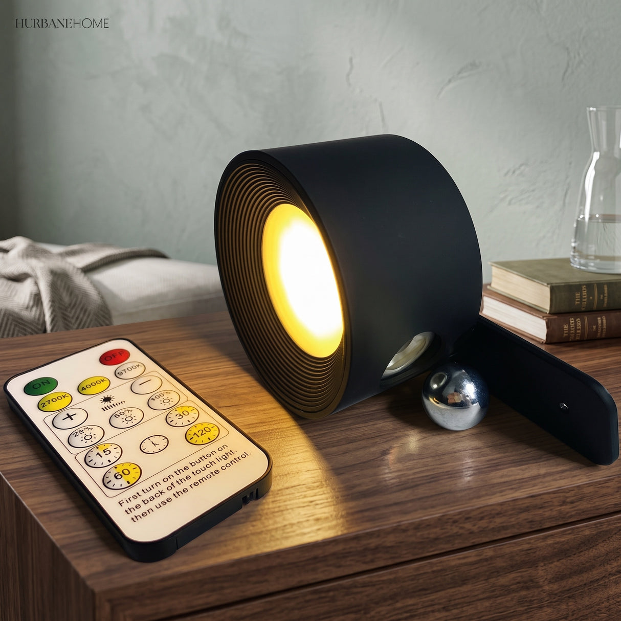 Black rotating wall light on a wooden shelf beside its remote control