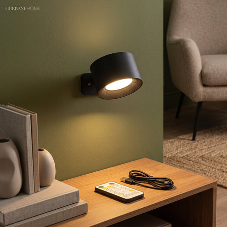 Black puck sconce lit on a green wall above a bookshelf