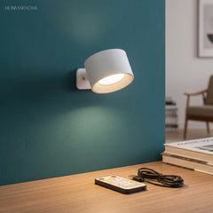 White cordless sconce lit against a deep teal painted wall