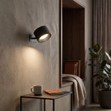 Black cordless puck wall light lit beside a doorway and side table
