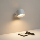 White cordless sconce lit above a shelf beside a remote and cable