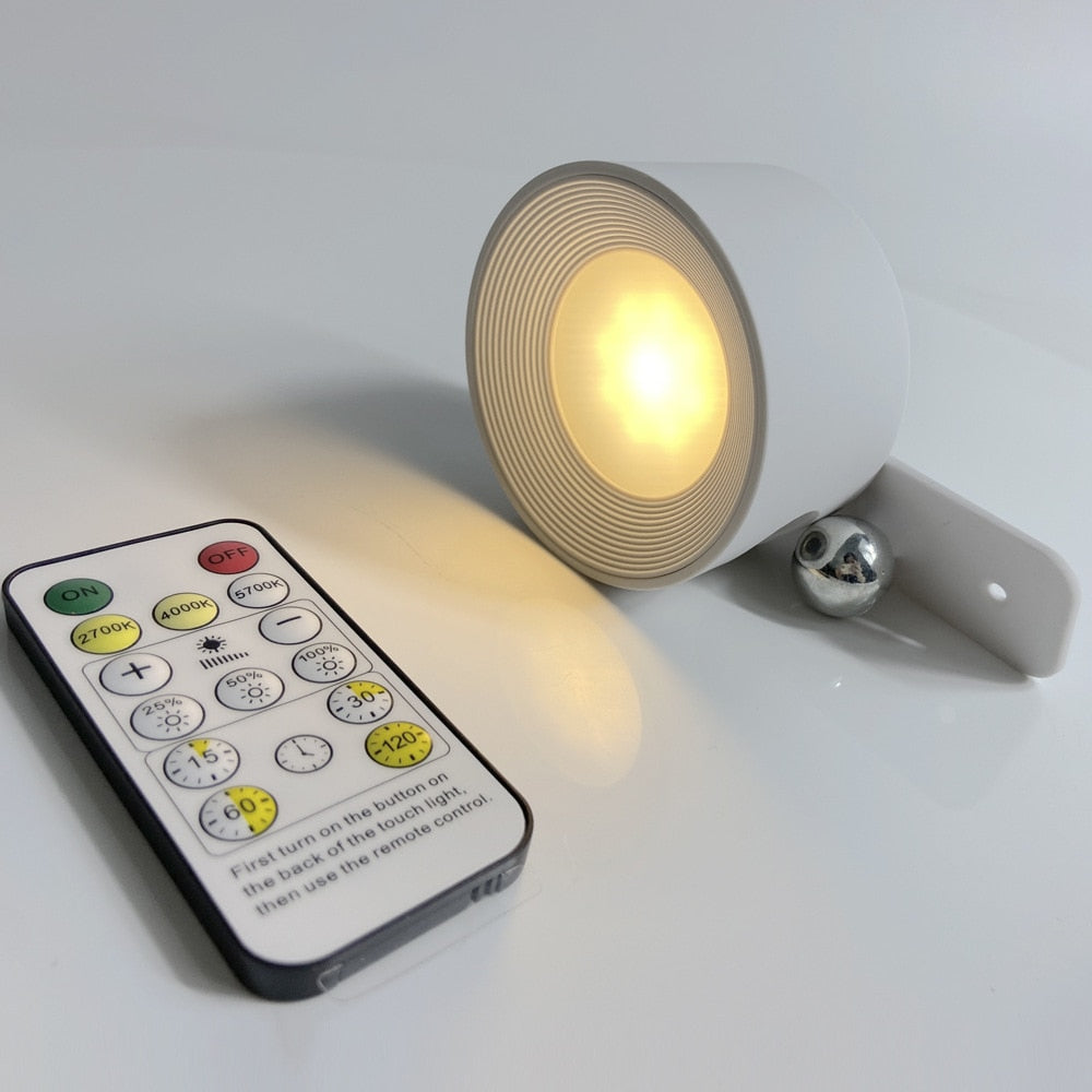 White puck light tilted on its mount beside a slim remote control