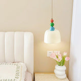 Beaded pendant lit beside a padded headboard and a vase of pink tulips