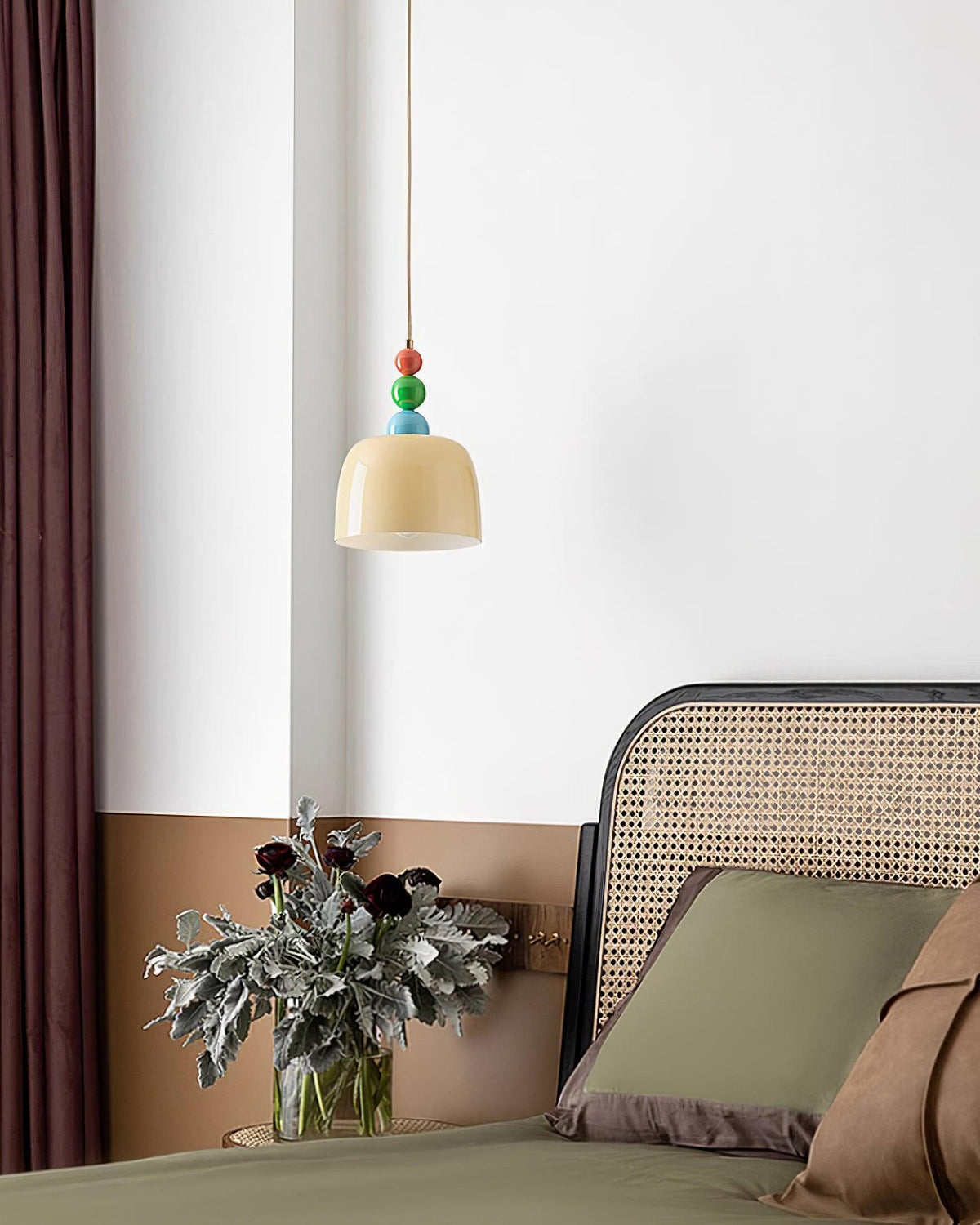Beaded pendant hung in a corner above a cane backed chair and a plant