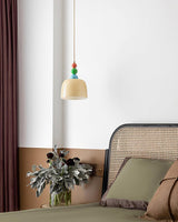 Beaded pendant hung in a corner above a cane backed chair and a plant