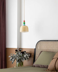 Beaded pendant hung in a corner above a cane backed chair and a plant