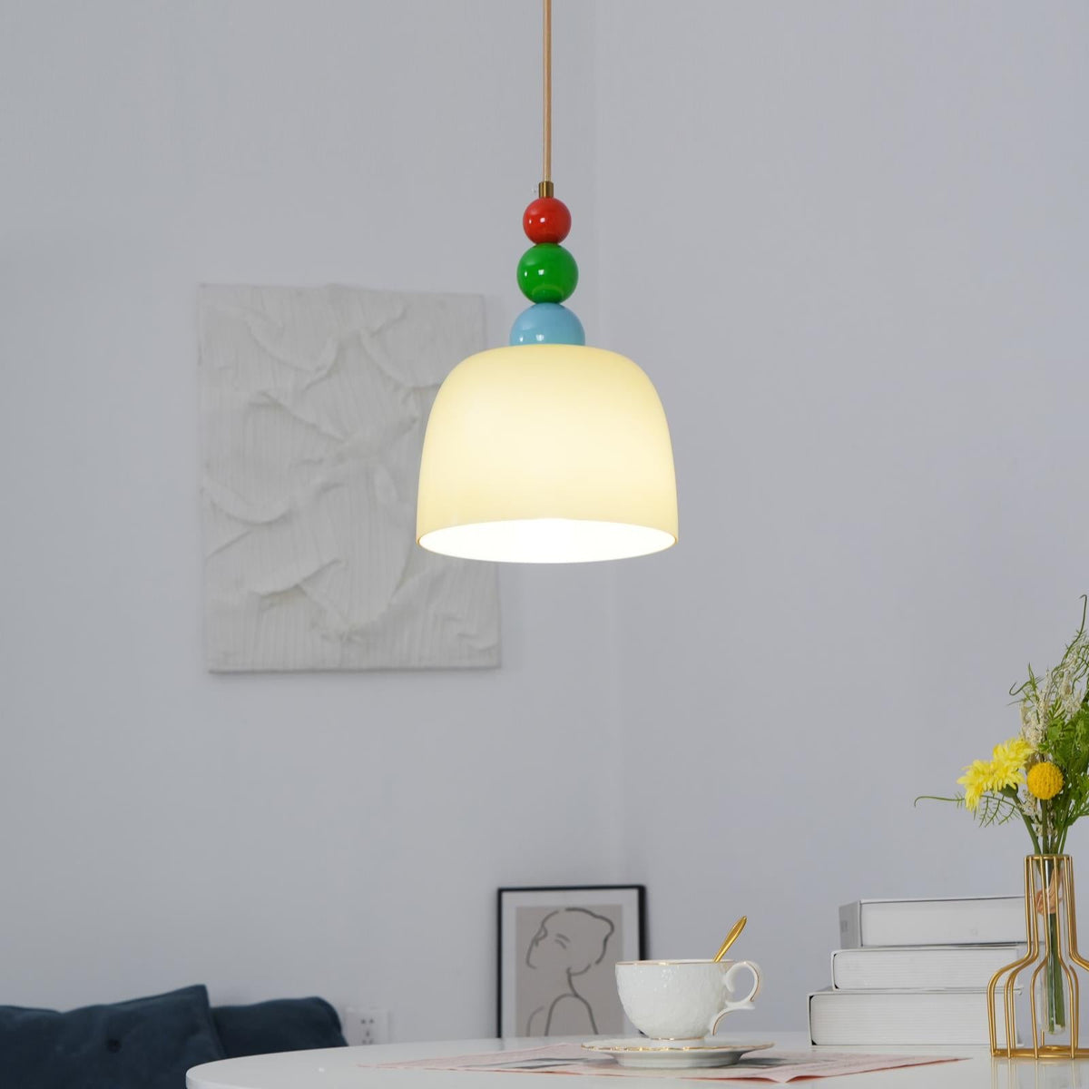 Glass dome pendant above a desk with stacked books, a coffee cup and tulips
