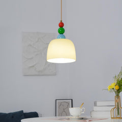 Glass dome pendant above a desk with stacked books, a coffee cup and tulips