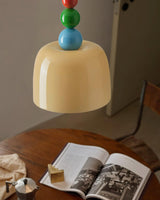 Beaded pendant lit closely above a timber desk with an open magazine
