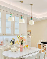 Row of three beaded pendants above a white kitchen table and cabinetry