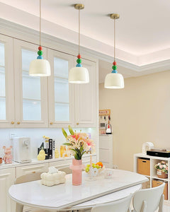 Row of three beaded pendants above a white kitchen table and cabinetry