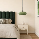 Green glass pendant light beside a bed in a bedroom corner