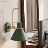 Green cone wall sconce beside a bedroom mirror and made bed