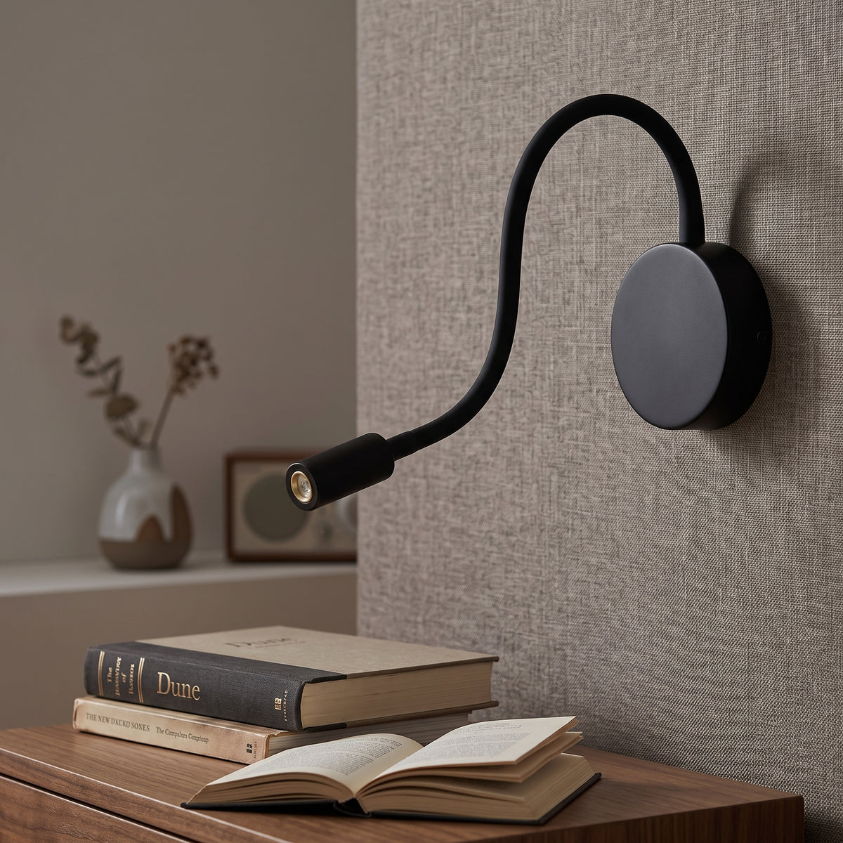 Black gooseneck reading light above a bedside table and open book