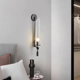 Black fluted glass sconce lit beside a bed and a wardrobe