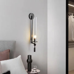Black fluted glass sconce lit beside a bed and a wardrobe