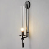 Black fluted glass sconce with an exposed candle bulb lit warm