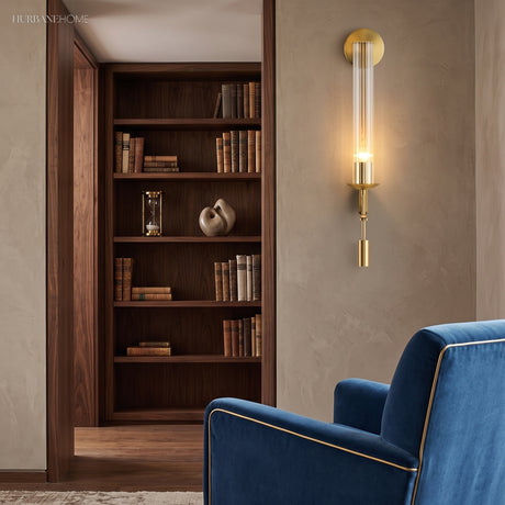 Gold fluted sconce lit beside a walnut bookcase and blue chair