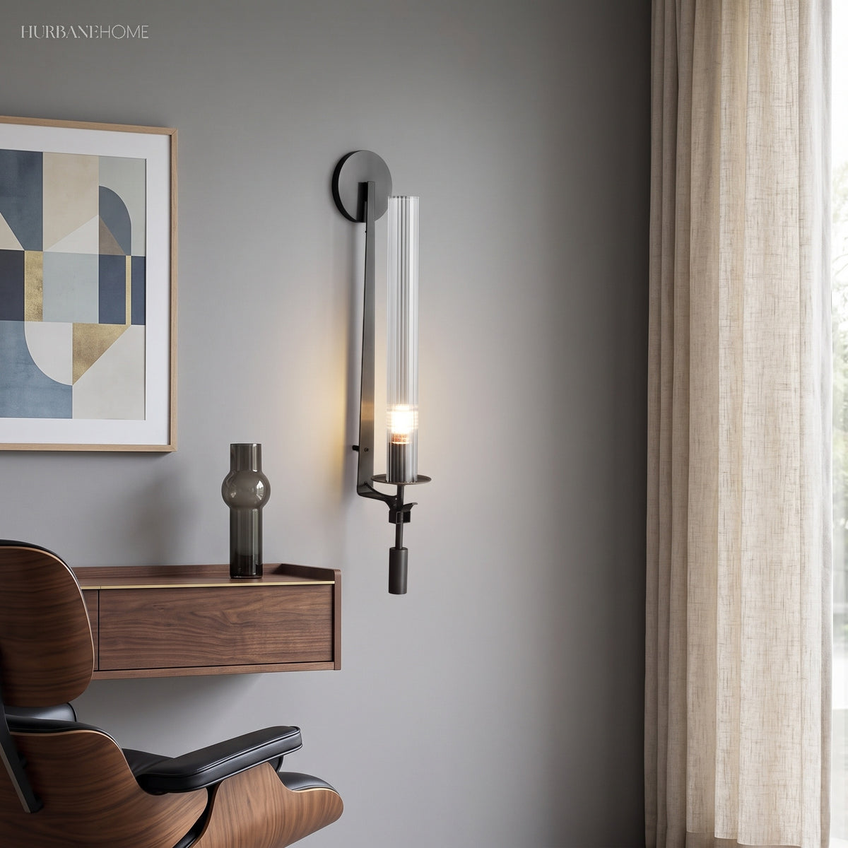Black fluted glass sconce lit above a desk and leather chair