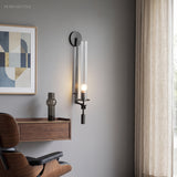 Black fluted glass sconce lit above a desk and leather chair
