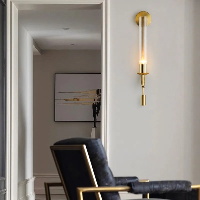 Gold fluted glass sconce lit in a hallway beside a doorway