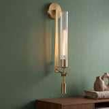 Gold candle style wall sconce with a fluted glass tube on green