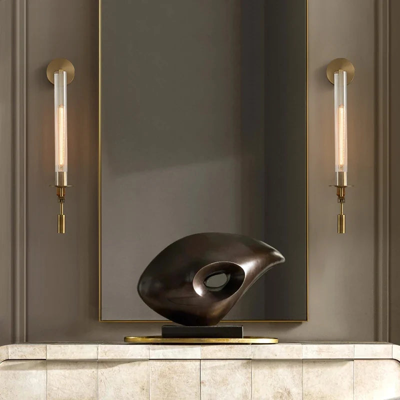 Two gold fluted sconces either side of a mirror above a mantel