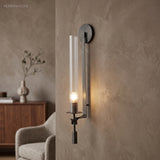 Black fluted glass sconce lit warm on a plaster wall
