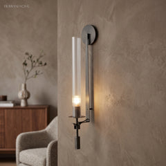 Black fluted glass sconce lit warm on a plaster wall