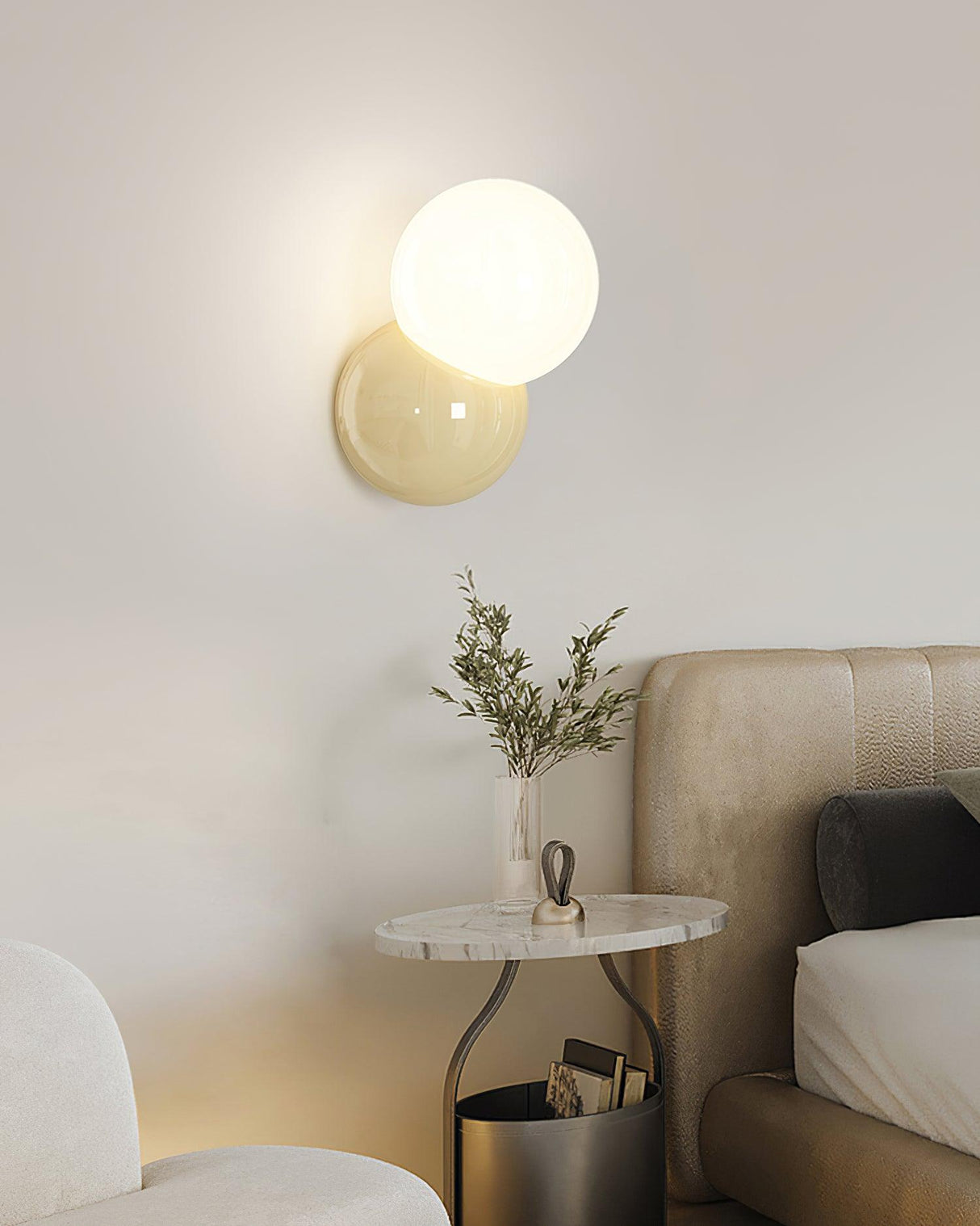 Wall sconce lit above a marble side table beside an upholstered bed head