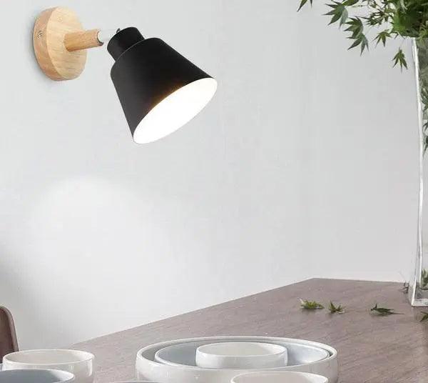 Black bell shade sconce on a wood mount against a white wall