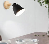 Black bell shade sconce on a wood mount against a white wall