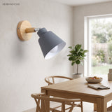 Grey bell shade sconce lit on a wall beside a dining table