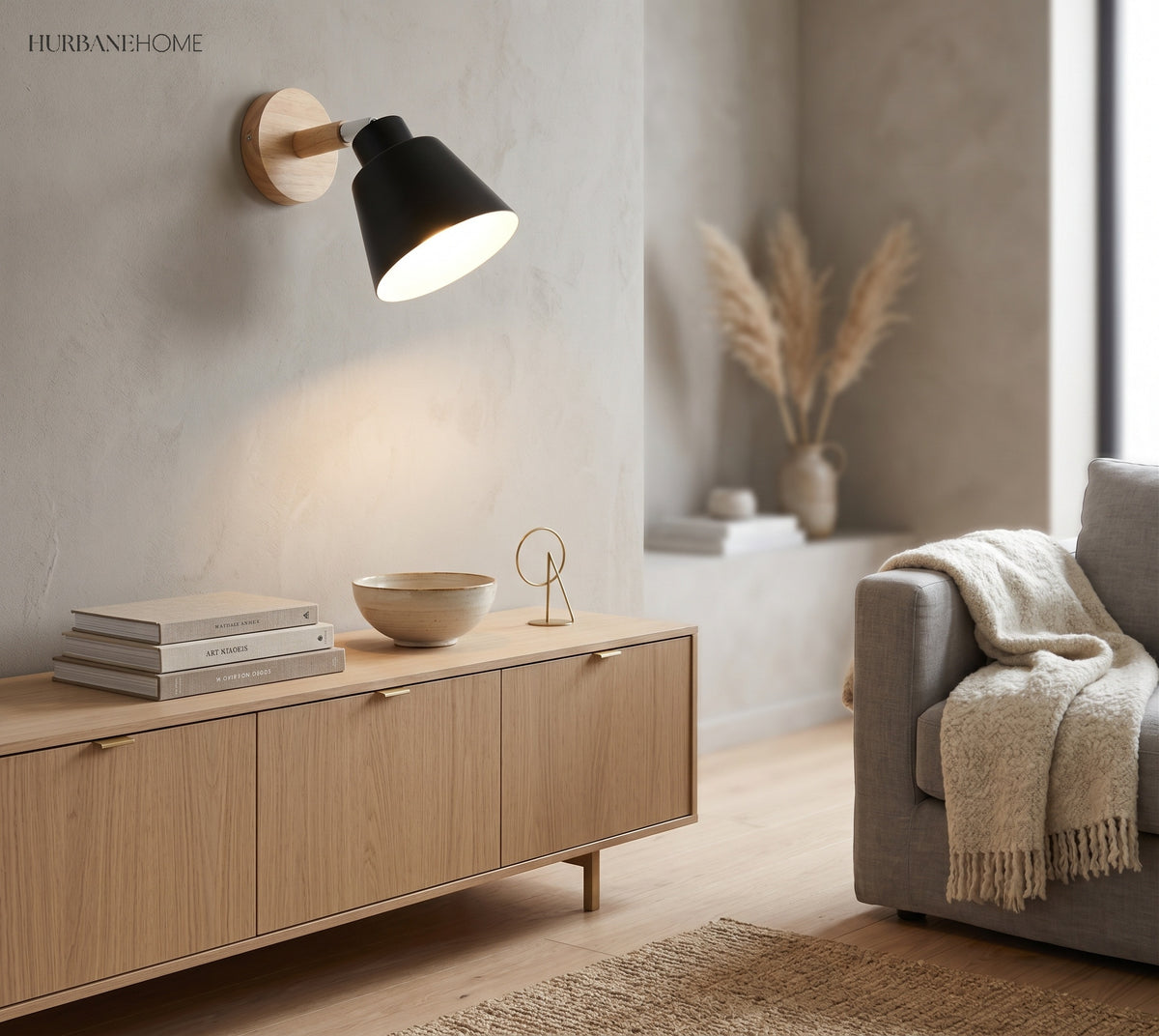Black bell shade sconce on a wood mount lit above a sideboard
