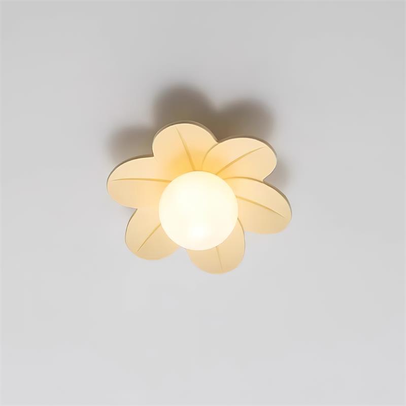 Beige petal ceiling light lit against a plain wall with a warm glass globe
