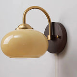 Beige oval glass sconce with pull-chain switch on ash wood plate