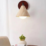 Beige travertine cone wall light against a plaster wall