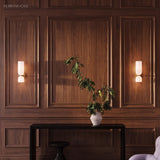 Pair of glass wall sconces on a walnut panelled wall above a console table