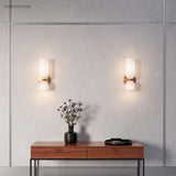 Two glass wall sconces above a timber console table in a hallway