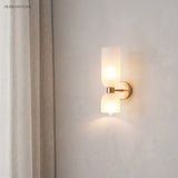 Glass wall sconce lit beside linen curtains in a quiet corner